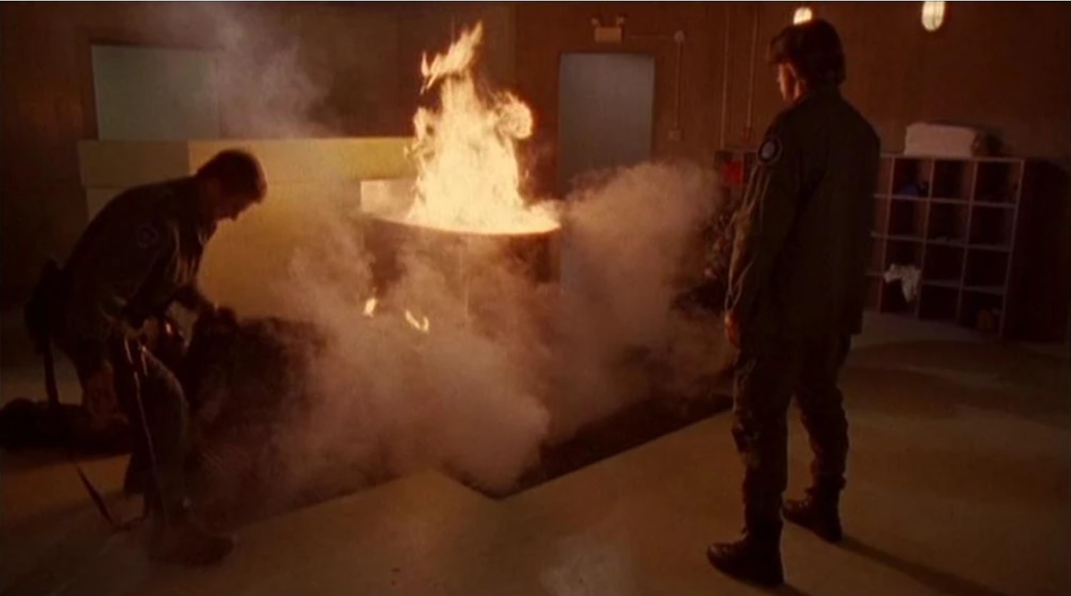 Still from the episode in question. Daniel watches as the human/alien hybrid breeding tank burns.