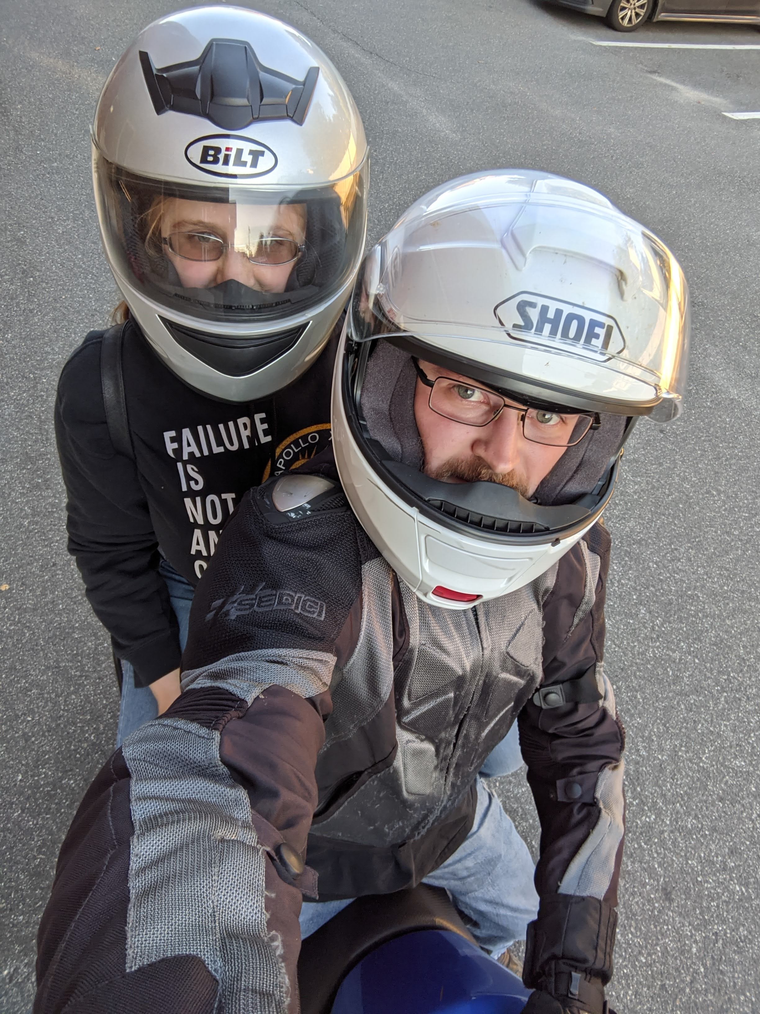 Bryan & Claire on a motorcycle. Both wearing helmets. Claire has on a sweatshirt that says "failure is not an option."