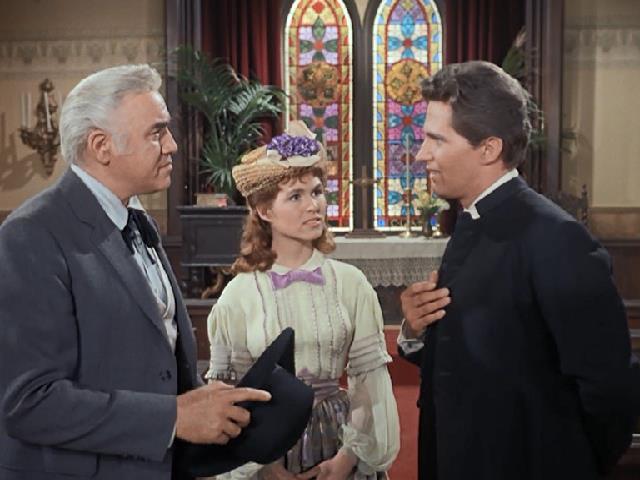 Ben Cartwright and a young woman speak to a minister in front of a stained-glass window